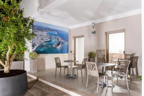 a room with tables and chairs and a painting on the wall at Cinque Venti BB Porto Cesareo in Porto Cesareo