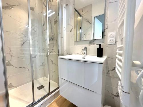une salle de bain blanche avec un lavabo et une douche dans l'établissement Bel appart Bd Foch, à Angers