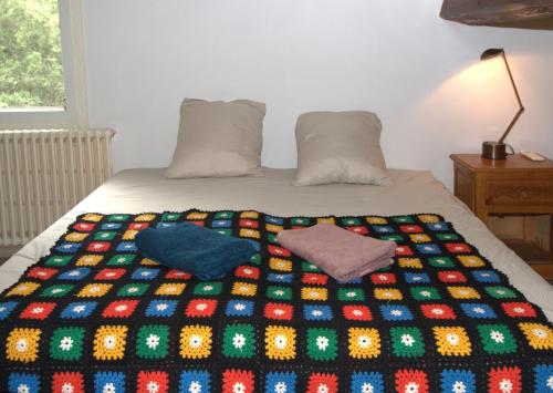 a bed with a colorful blanket and two pillows on it at Zen Experience including Yoga & Healthy food in Ladern-sur-Lauquet