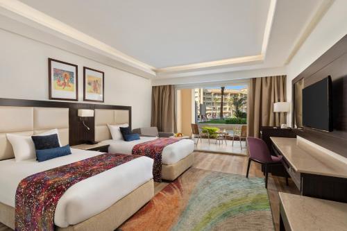 a hotel room with two beds and a flat screen tv at Pickalbatros White Beach Resort - Hurghada in Hurghada