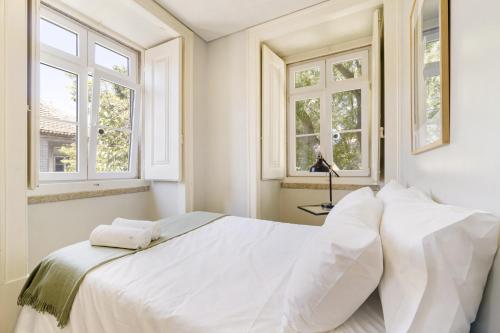 uma cama branca num quarto com janelas em Metropolitan Living Lisbon - Janelas Verdes em Lisboa