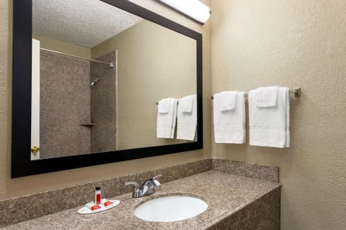 a bathroom with a sink and a mirror and towels at Super 8 by Wyndham Gainesville TX in Gainesville