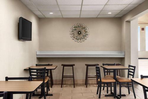 a dining room with tables and chairs and a clock on the wall at Super 8 by Wyndham Gainesville TX in Gainesville