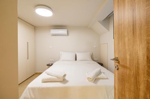 a bedroom with a bed with white sheets and towels on it at Modern ground floor apt near the park in Athens