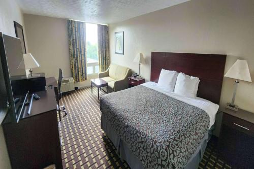 a hotel room with a bed and a chair at Days Inn by Wyndham Fort Wright Cincinnati Area in Fort Wright