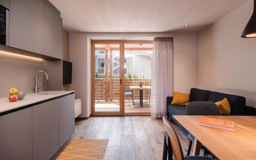 Il dispose d'une cuisine et d'un salon avec un canapé et une table. dans l'établissement Max Green Wood Apartments, à Alpe di Siusi