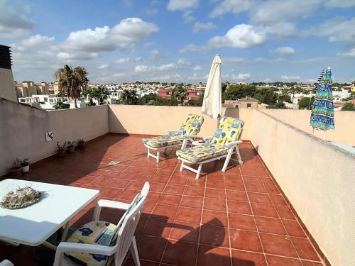 a patio with chairs and a table and umbrella on a roof at Casa Castillo Penthouse with balcony and solarium near La Zenia boulevard in Orihuela