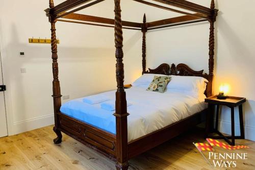 Cama con dosel en un dormitorio con suelo de madera en Bridge End House - Country & Riverside Retreat, en Haltwhistle