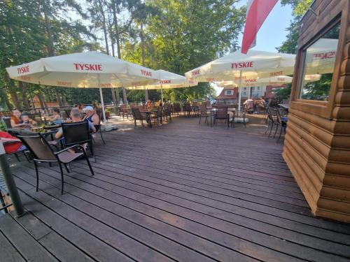 a wooden deck with tables and chairs and umbrellas at Ośrodek Promenada- Horyzont in Jastrzębia Góra