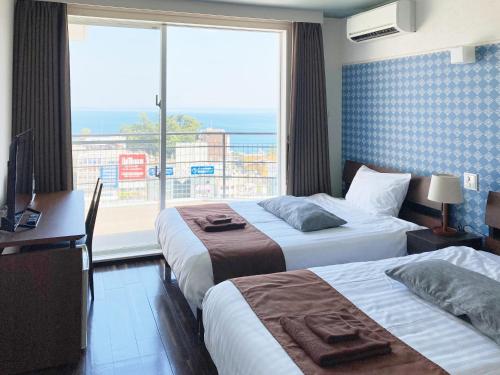 a hotel room with two beds and a large window at Chateraise Lodge Atami in Atami