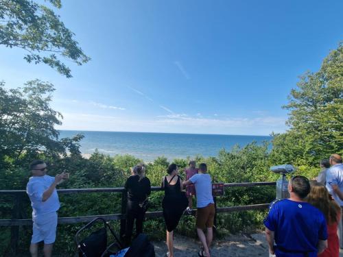 a group of people standing on a fence looking at the ocean at Ośrodek Promenada- Faleza in Jastrzębia Góra