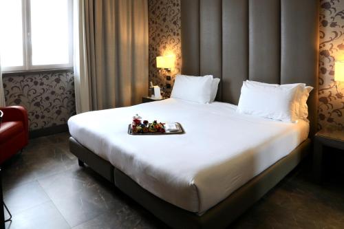 a hotel room with a bed with a tray of food on it at Klima Hotel Milano Fiere in Milan