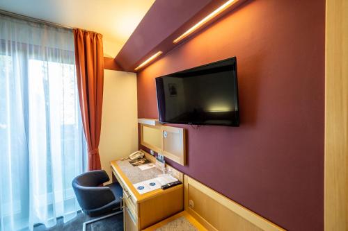 um quarto de hotel com uma televisão numa parede vermelha em Jan Maria Hotel & Restaurant em Ostrava