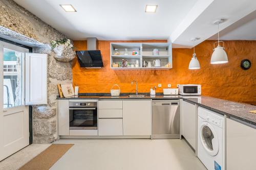 a kitchen with white appliances and an orange wall at Casa do Pomar - Manor House in Taide