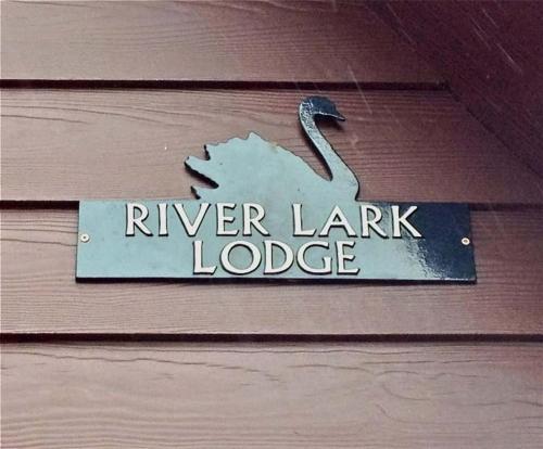 um sinal que diz alojamento de empréstimo de rio numa parede de madeira em River Lark Lodge em Ely