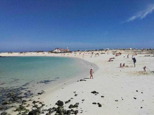 a group of people on a beach near the water at El Cotillo On The Beach by Momi Fuerteventura in Cotillo