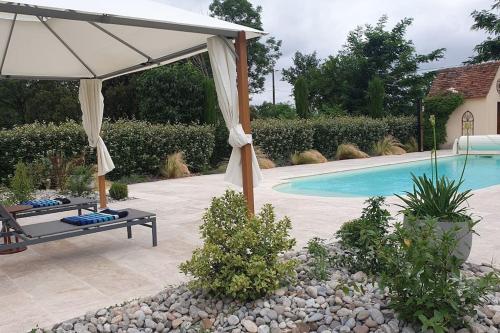 un patio avec un parasol et une piscine dans l'établissement Gîte à Montvalent, proche Rocamadour, Adult only, à Montvalent