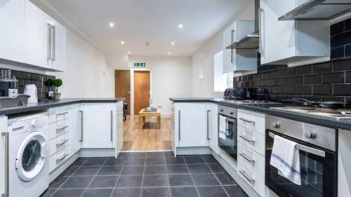 a kitchen with white cabinets and a washer and dryer at Kelvin Grove by UStay in Liverpool
