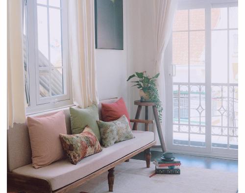 a couch with pillows sitting in a room with a window at Le Macaron City Center - Boutique Hotel Đà Lạt in Da Lat