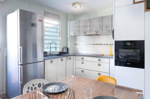 una cocina con armarios blancos y una mesa de madera con sillas. en Karédor-Appartement 4 personnes , proche du centre-ville de Saint-Denis, en Saint-Denis