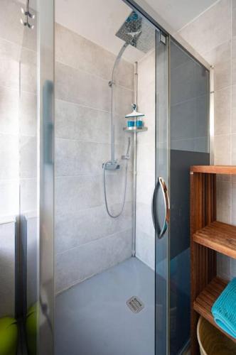La salle de bains est pourvue d'une douche avec une porte en verre. dans l'établissement Karédor-Appartement 4 personnes , proche du centre-ville de Saint-Denis, à Saint-Denis