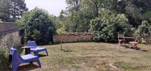 a yard with chairs and a table and a brick wall at Chambre d'hôtes La grange in Chalagnac