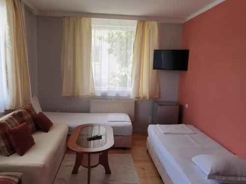 ドブリニシュテにあるMira Guest Houseのベッド2台、ソファ、テーブルが備わる客室です。