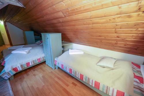 two beds in a room with wooden walls at Wenckheim Vadászház in Nagyoroszi
