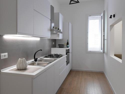 a white kitchen with a sink and a stove at A CANTUNERA in Balestrate