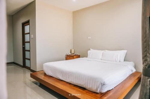 a bedroom with a large white bed with a wooden bench at โรงแรม ณ สุโขทัย in Sukhothai