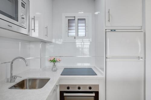 cocina blanca con fregadero y nevera en Vistamarina A409 By IVI Real Estate, en Torremolinos