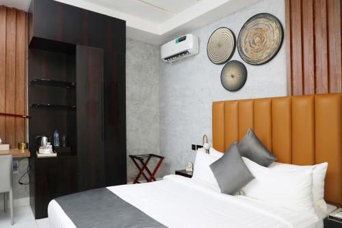 a bedroom with a white bed with a wooden headboard at Westine Hotels and Spa in Lagos
