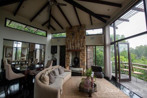 a living room with a couch and a fireplace at Tsala Treetop Lodge in Plettenberg Bay