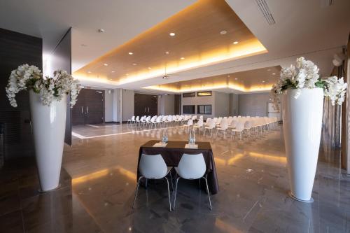 a banquet hall with a table and chairs and vases with flowers at Klima Hotel Milano Fiere in Milan