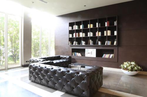 a living room with a leather couch and a book shelf at Klima Hotel Milano Fiere in Milan
