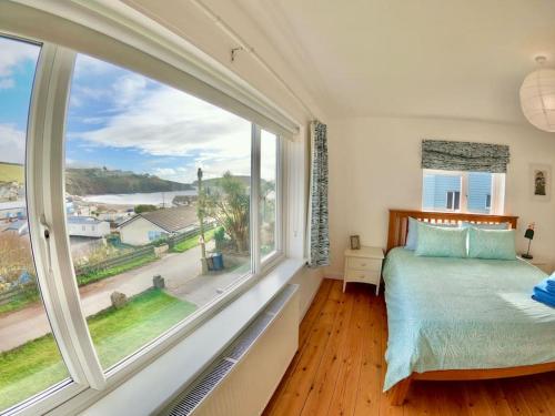 een slaapkamer met een groot raam en een groot bed bij Modern Beach House overlooking the Sea in Bigbury