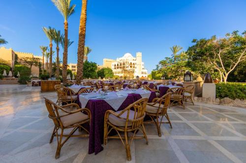 a restaurant with tables and chairs and palm trees at Makadi Palace - Couples and Families Only in Hurghada