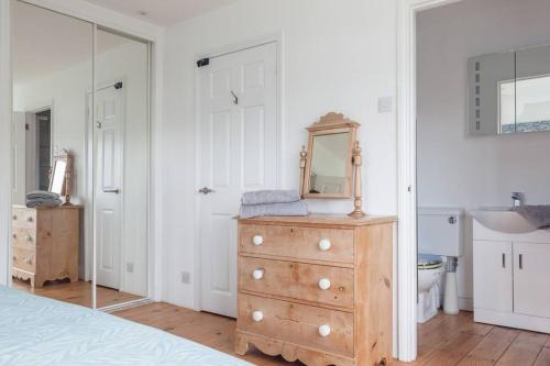 een slaapkamer met een dressoir met een spiegel en een wastafel bij Modern Beach House overlooking the Sea in Bigbury