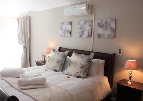 um quarto com uma cama com lençóis brancos e almofadas em Hoopstad Guesthouse em Hoopstad