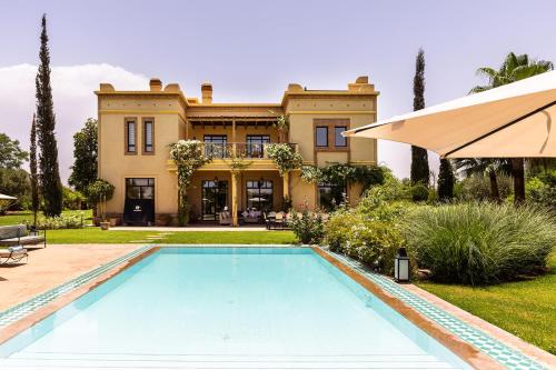 a villa with a swimming pool in front of a house at Villa de Luxe avec Piscine Privée et Golf in Marrakesh