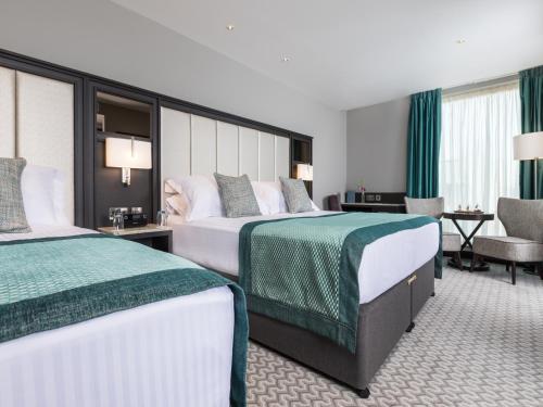 a hotel room with two beds and a chair at Grand Central Hotel Belfast in Belfast