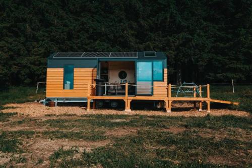 a tiny house with a deck on a field at Tiny House Rákosníček in Malšín