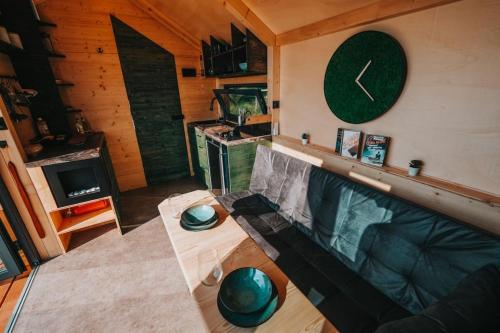 a living room with a couch and a clock on the wall at Tiny House Rákosníček in Malšín