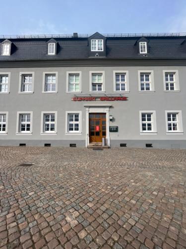 un gran edificio blanco con un letrero rojo. en Euphrat Pension en Lichtentanne