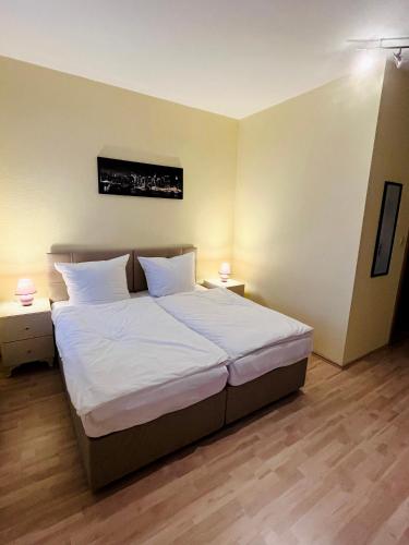 um quarto com uma cama grande e lençóis brancos em Euphrat Pension em Lichtentanne