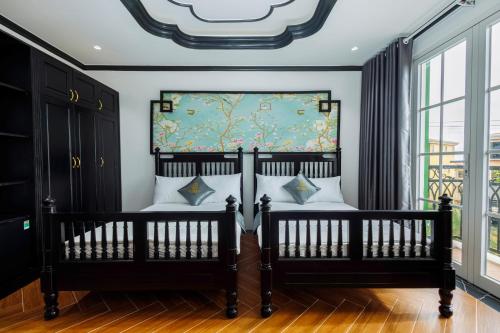 2 czarne łóżka w pokoju z oknem w obiekcie De Stefano Coffee and Hotel w Duong Dong