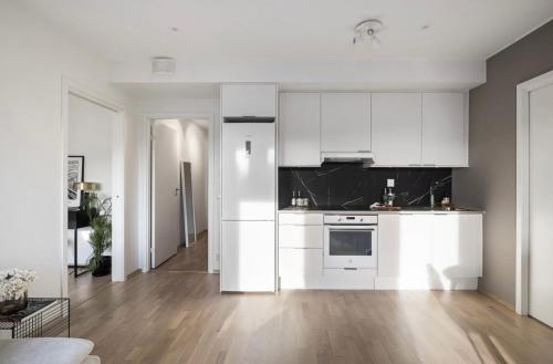 a white kitchen with white cabinets and a wooden floor at Private room in sharded apartment at Løren in Oslo