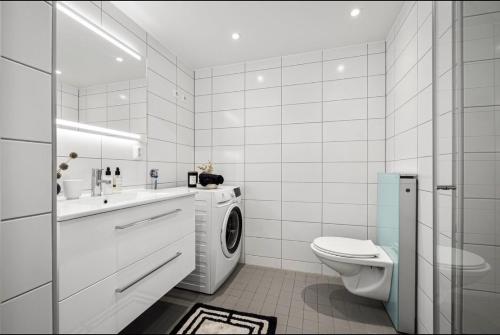 a white bathroom with a washing machine in it at Private room in sharded apartment at Løren in Oslo