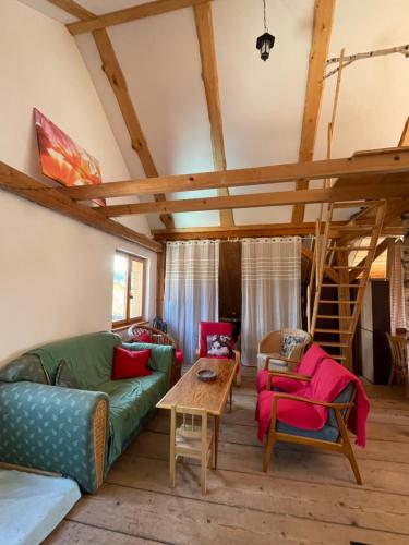 a living room with a green couch and red chairs at Apartmán Půda Lhotka in Klášterec nad Orlicí