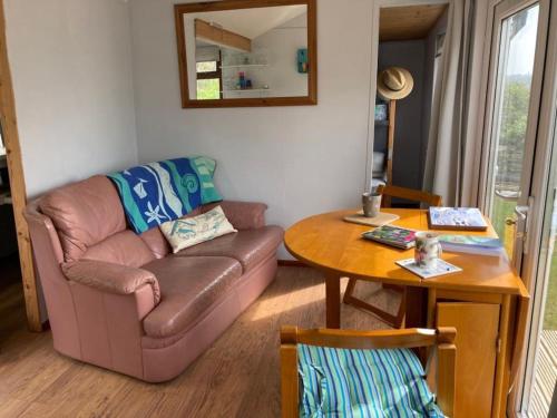 a living room with a couch and a table at Cliff top Chalet with fantastic sea views in Cornwall. in Cawsand